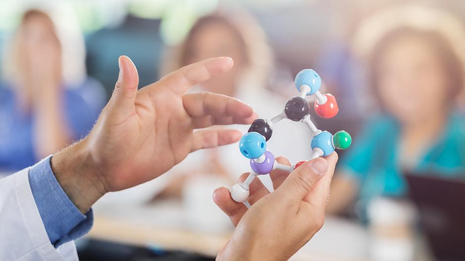 Teacher holding an atom model in from of a class